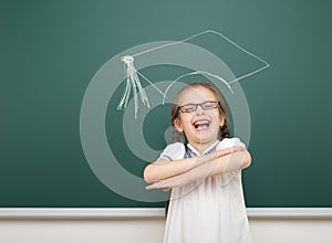 Girl with academic cap drawing on school board