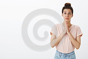 Girl acting like angel as begging for favour or help holding hands in pray making nice sincere expression being in need