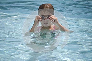 Girl adjusting goggle in pool