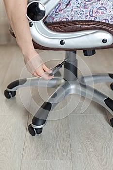 The girl adjusts the height of the new brown office chair.