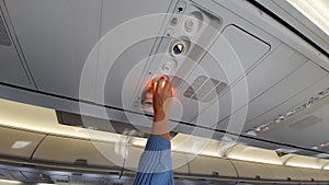 Girl adjusts the light in the plane cabin.