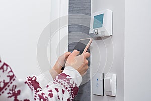 Smart Home Comfort: Woman Controlling Temperature with Smart Phone