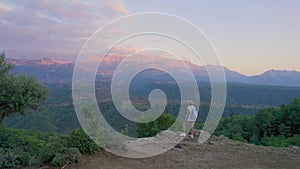 The girl admires the picturesque view in the mountains at sunset.