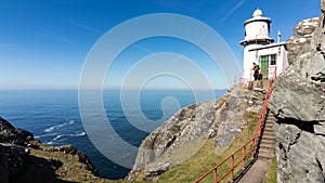 Girl admiring the Atlantic Ocean from a big lighthouse placed on the shoreline