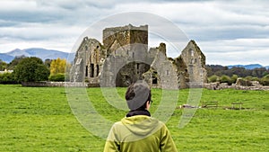 Girl admiring the ruins of a castle situated near a lake in Ireland highlands