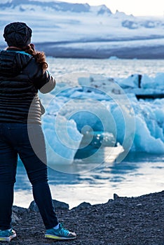 Girl admiring the scenery with ice depths in the famous Jokulsarlon glacial lagoon in Iceland. Exotic countries. Amazing places.