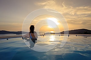 Girl admiring sunset from the pool. Summer vacation holiday