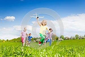 Girl with airplane toy runs fast and kids behind