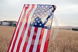 Girl with american flag smiling in the sunset. Young woman playing with USA flag in the 4th of July.