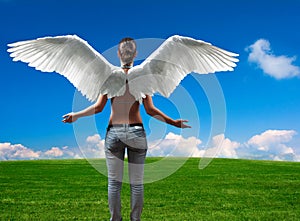 Girl with angel wings standing on the meadow