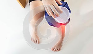 A girl applies a blue medical bag with ice to her knee joint for a bruise on her knee. Local cryotherapy. Pain relief