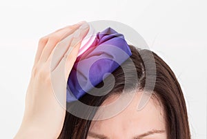 The girl applies a medical ice pack to her head. The concept of eliminating headaches from nervous overstrain with the help of