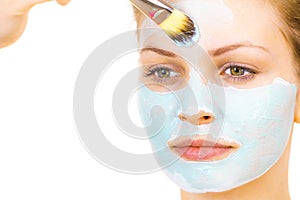 Girl apply green mud mask to face