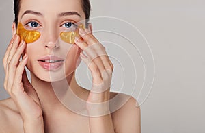 Girl applying golden collagen patches under the eyes. Remove wrinkles and dark circles