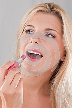 Girl applying pink lip stick