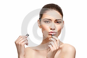Girl applying pink lipstick isolated on white