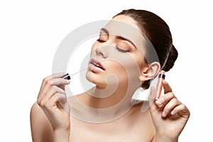 Girl applying pink lipstick isolated on white