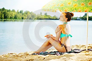 Girl applying sun tan cream on her skin
