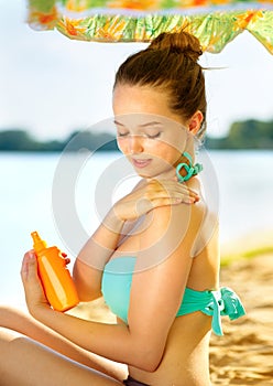 Girl applying sun tan cream on her skin