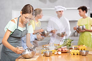 Girl in apron learns to cook at master class