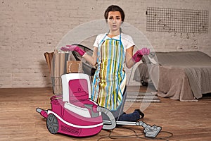Girl in an apron, rubber gloves and red lips has opened the lid of the cartoon vacuum cleaner and looking confused.
