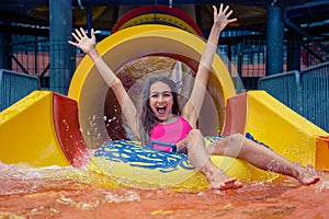 Girl in aqua park have fun riding on water slide with inflatable ring