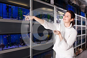 Girl in aquarium shop points to colored fish