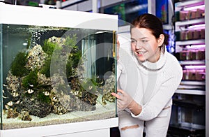 Girl in aquarium shop points to colored fish