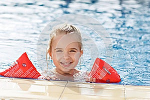 The girl in the arm ruffles in the pool smiling