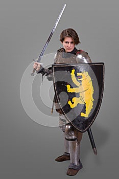 Girl in armor with a sword knight wuth shield over grey background