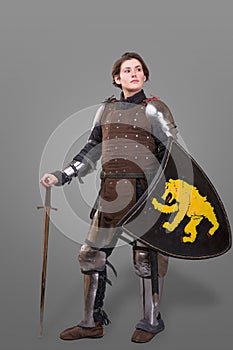 Girl in armor with a sword knight wuth shield over grey background