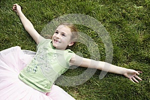 Girl With Arms Outstretched Lying On Grass