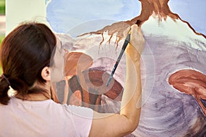 Girl artist hand holds paint brush and draws abstract nature landscape on canvas