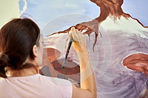 Girl artist hand holds paint brush and draws abstract nature landscape on canvas