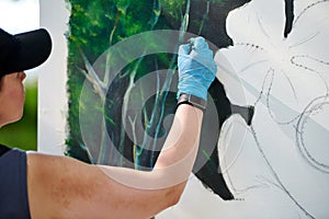 Girl artist hand holds paint brush and draws green nature landscape on canvas