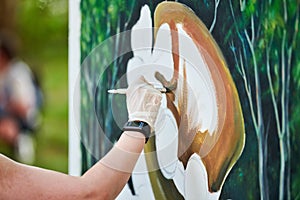 Girl artist hand holds paint brush and draws green nature landscape on canvas