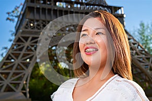 Girl of Asian appearance in a white T-shirt with braces, looks to the side and smiles, blurred background