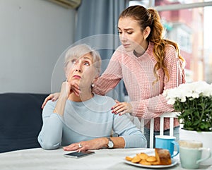 Girl asking for forgiveness from offended mother at home table