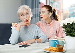 Girl asking for forgiveness from offended mother at home table