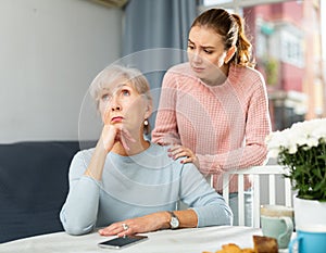 Girl asking for forgiveness from offended mother at home table