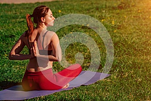 Girl athlete does a namaste pose from behind. young female body arms on sunset background outdoors