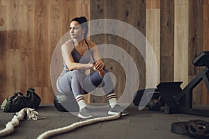 A girl athlete with a pumped-up booty squats with a phyto ball near the wall