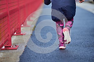 girl athlete in sportswear running young in boys' race, running in the details of the city on her legs