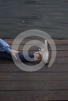 Girl with athletic body in blue gym suit is doing yoga exercises outdoors