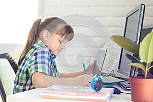 Girl attends school remotely through online video tutorial photo