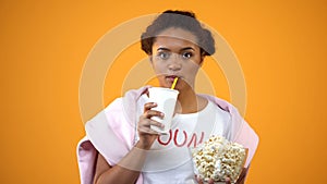 Girl attentively watching movie and drinking soft drink, influence of television