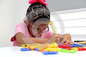 Girl with autism spectrum disorder ASD like Asperger, Rett and Heller draws at a desk, plays with colors alone antisocial