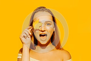 Girl with autumn leaves and red makeup, grimaces and has fun. Autumn photo on yellow background