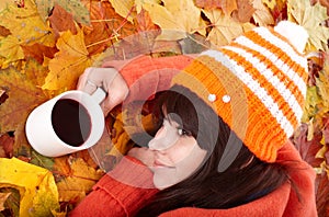 Girl in autumn orange foliage with coffee cup