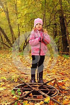 Girl in autumn park stand near rusty hatch